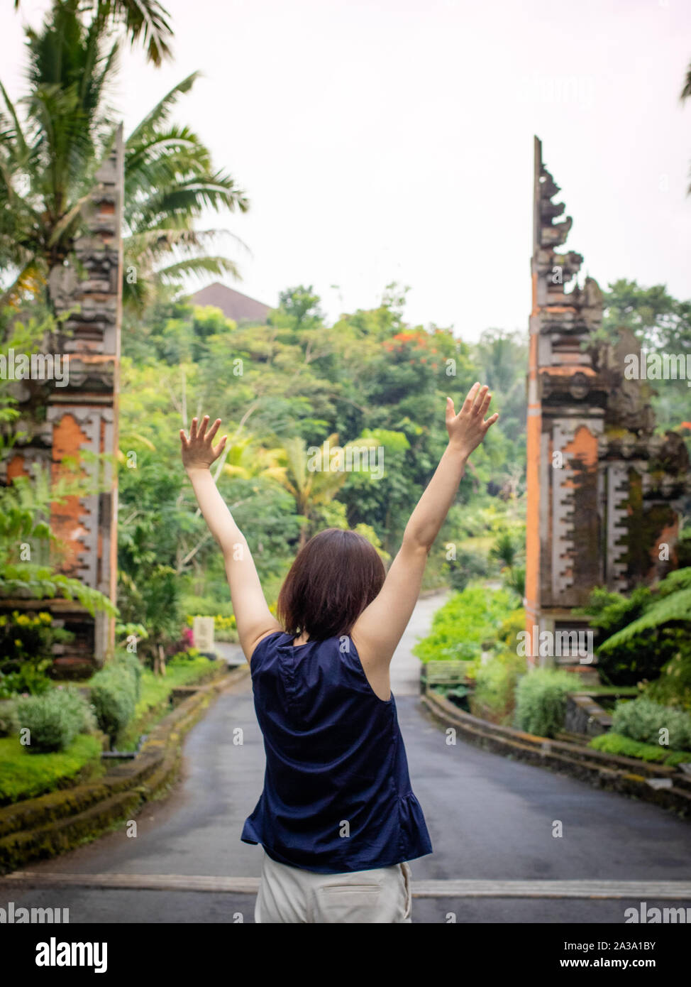 A beautiful female tourist in Bali, Indonesia, walking towards a Candi Bentar archway Stock Photo