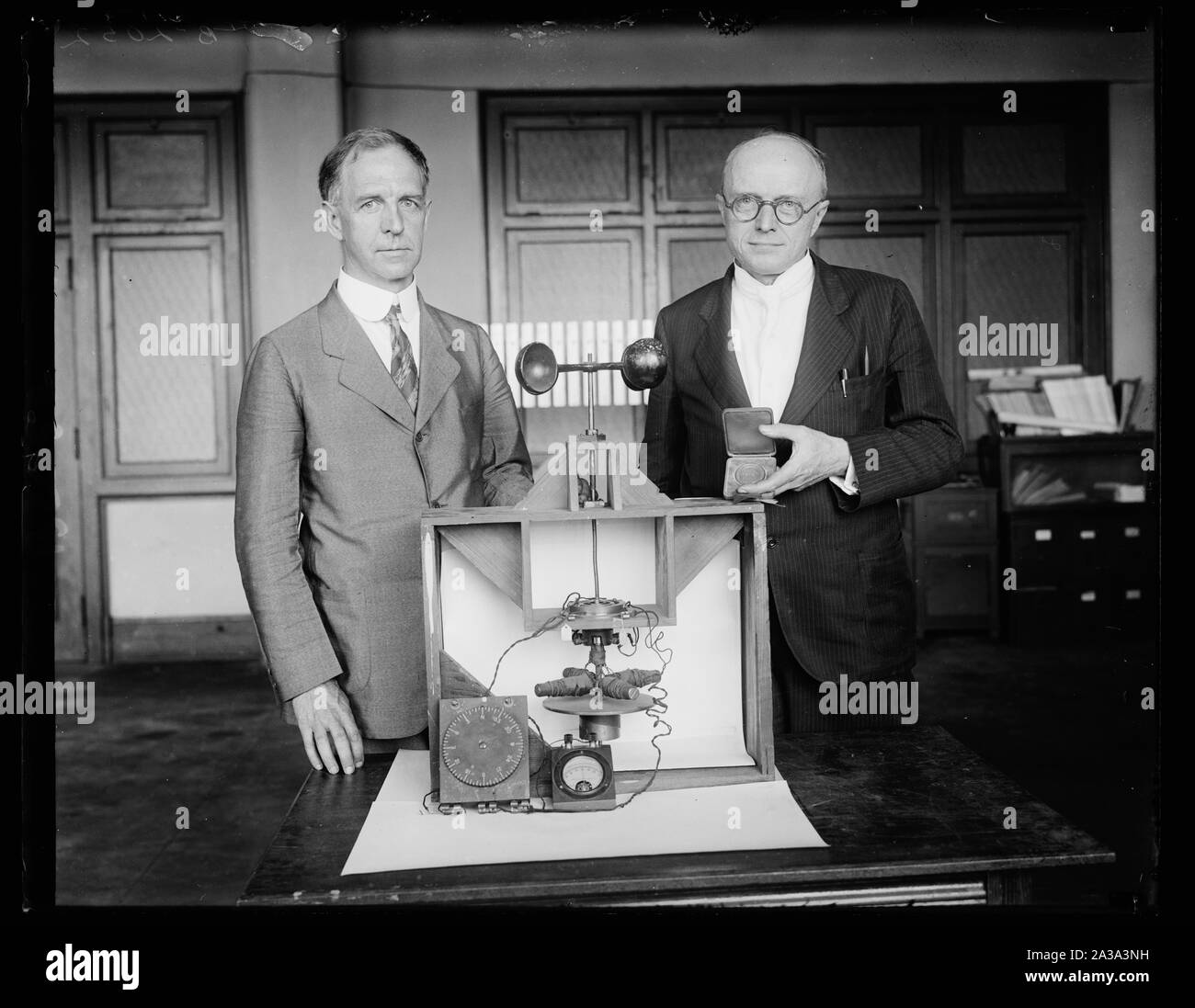 Scientists for Uncle Sam awarded Magellan Gold Medal. Dr. L.J. Briggs, left, Assistant Director and Dr. Paul R. [Heyl], Chief of the Sound Section of the United States Bureau of Standards, with the first successful experimental model of the earth inductor compass, which they developed for the Army Air Corps and for which they were awarded the Magellan Gold Medal by the American Philosophical Society. It was a model of this same compass that Capt. Charles Lindbergh used on his epochal flight from New York to Paris Stock Photo