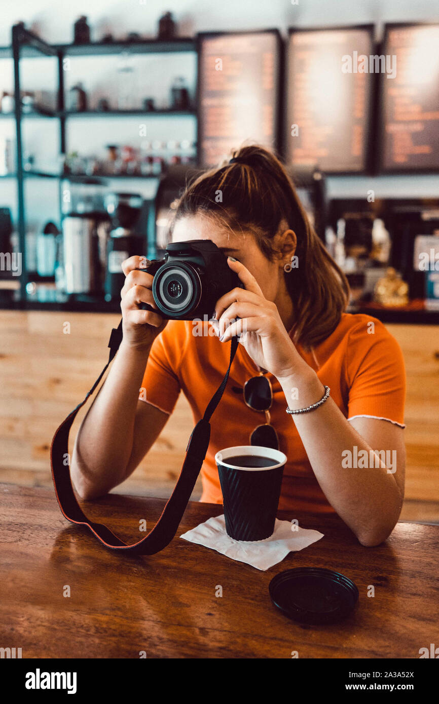 Girl at Coffee Shop Holding A Camera and Taking A Picture Stock Photo