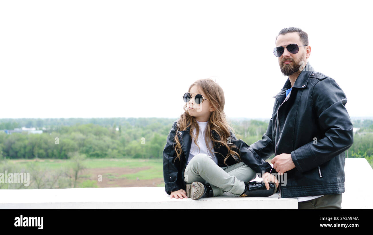 Fashionable stylish family for a walk. Charming schoolchild and her handsome young dad spend time together outdoors. Family look. Urban casual outfit. Stock Photo