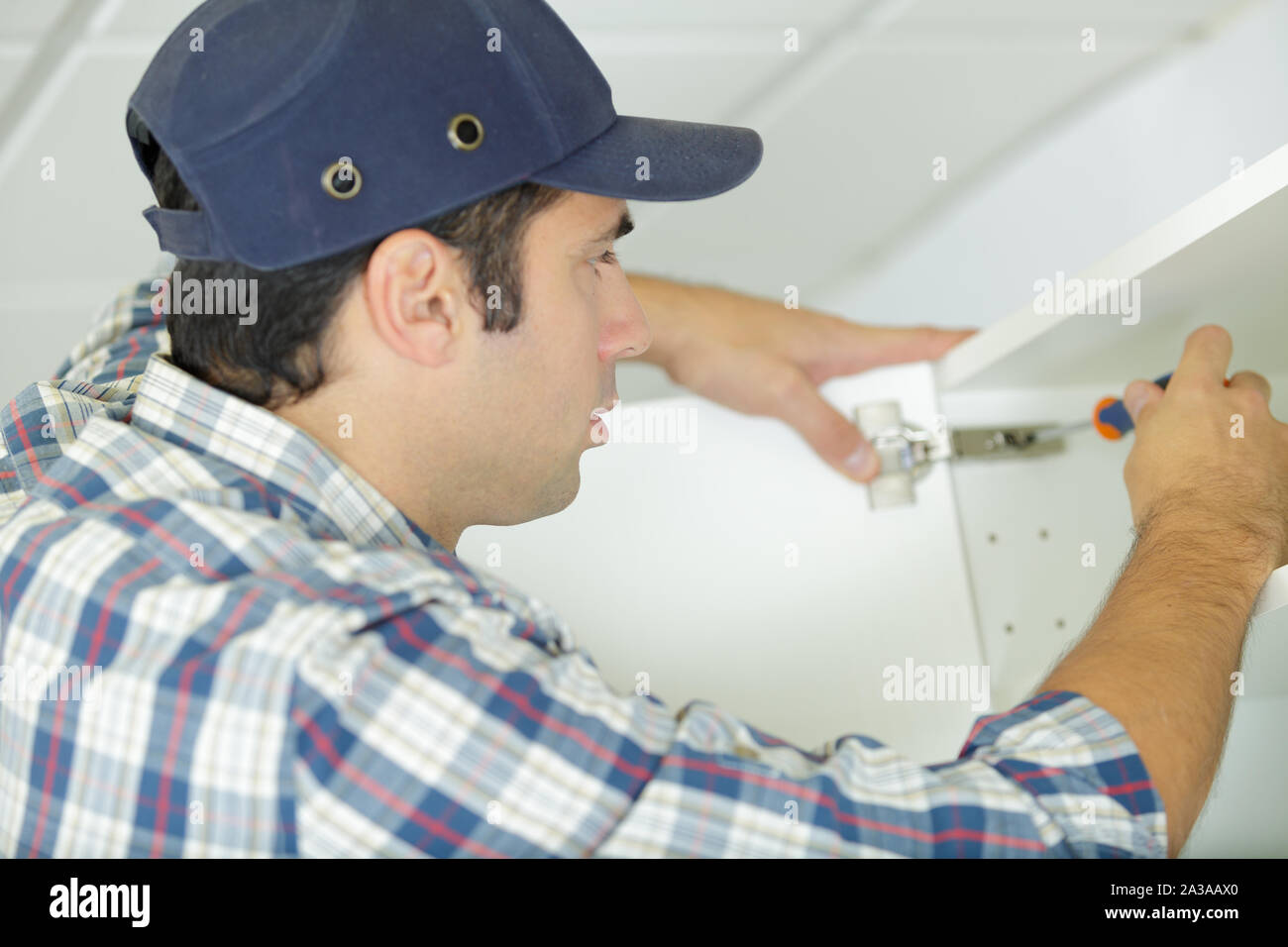 worker screws a cupboard with a screwdriver Stock Photo
