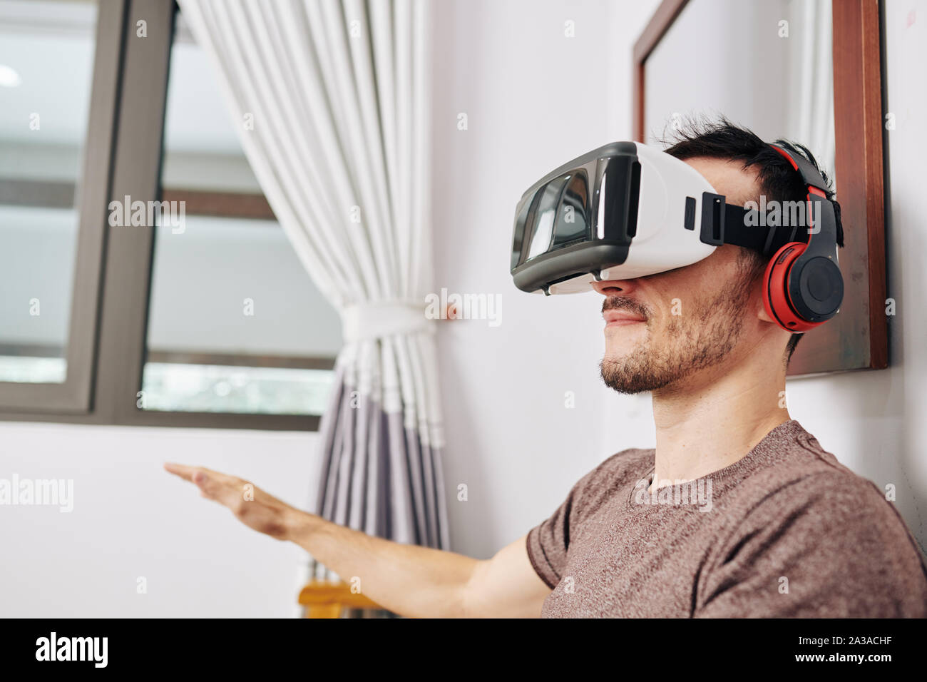 Positive young man wearing VR headset when testing new application he created Stock Photo