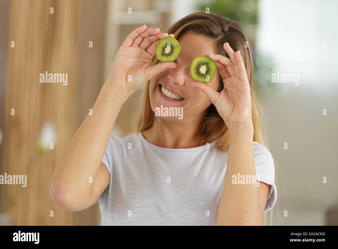 woman with kiwi slices in front of her eyes Stock Photo