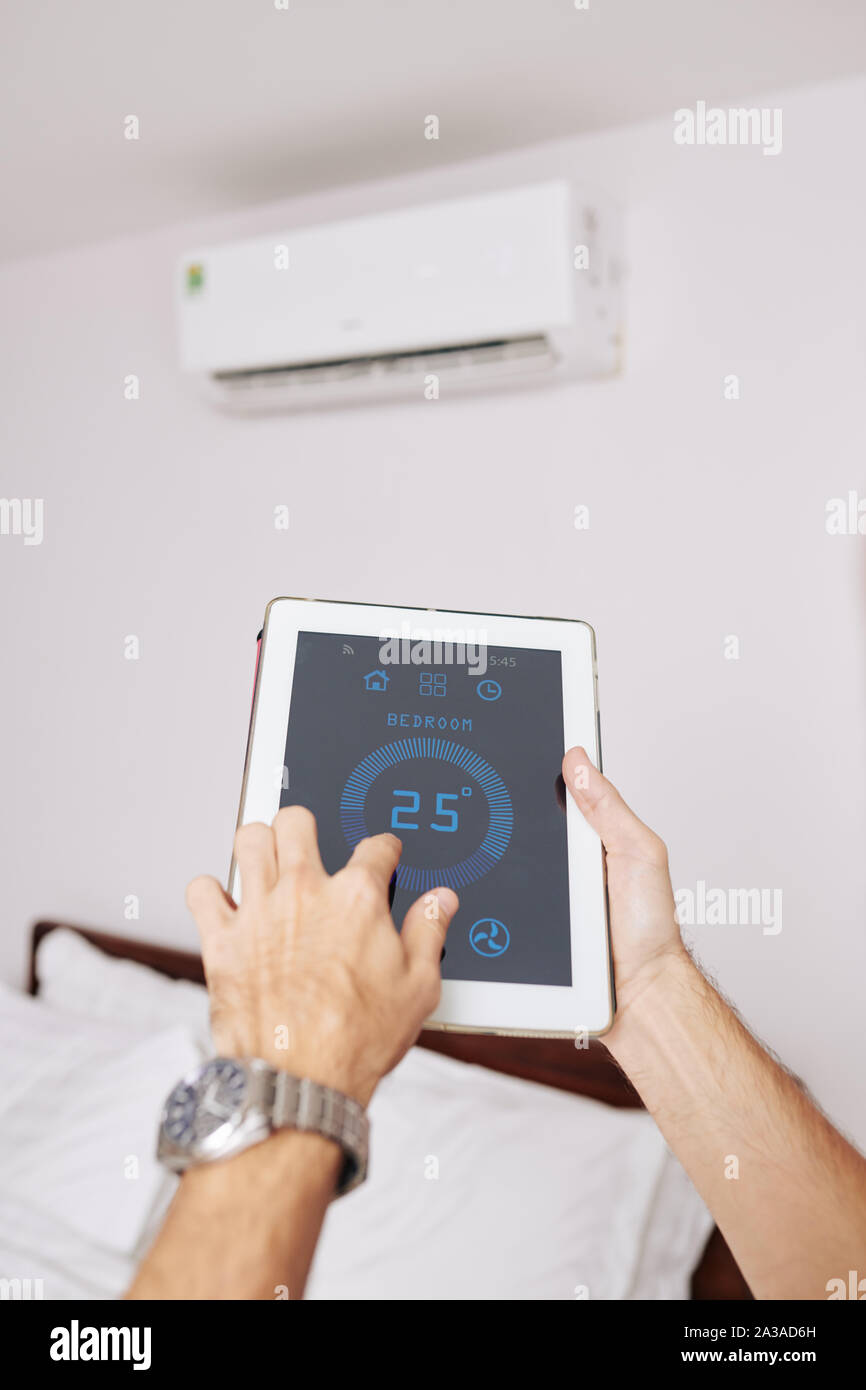 Hands of man using climate control application on tablet computer to regulate temperature in his room Stock Photo