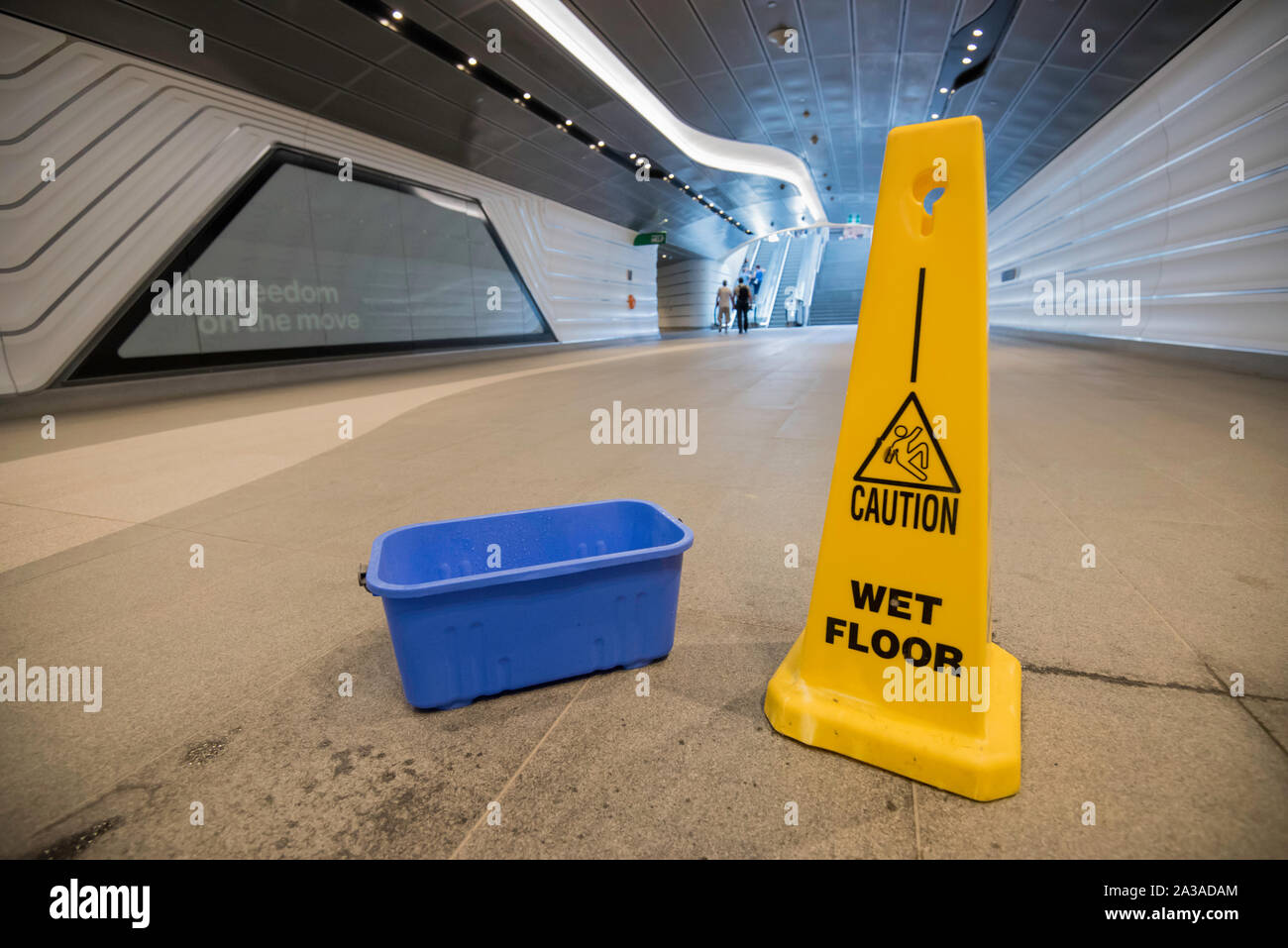 A bucket and a wet floor sign provide a different view of the relatively new Wynyard Walk pedestrian tunnel during a period of heavy rain in Sydney. Stock Photo