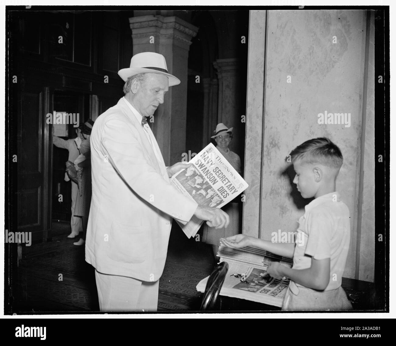 Sen. Ashurst buys paper announcing death of Secretary Swanson. Washington, D.C., July 7. Senator Henry Ashurst of Arizona, Chairman of the Senate Judiciary Committee shown here buying a newspaper at the Capitol today. The headlines announce the death of Navy Secretary Clyde Swanson this morning. News-vendor is 10 year old Benny Brown who operates the newsstand near the Senate Chamber Stock Photo