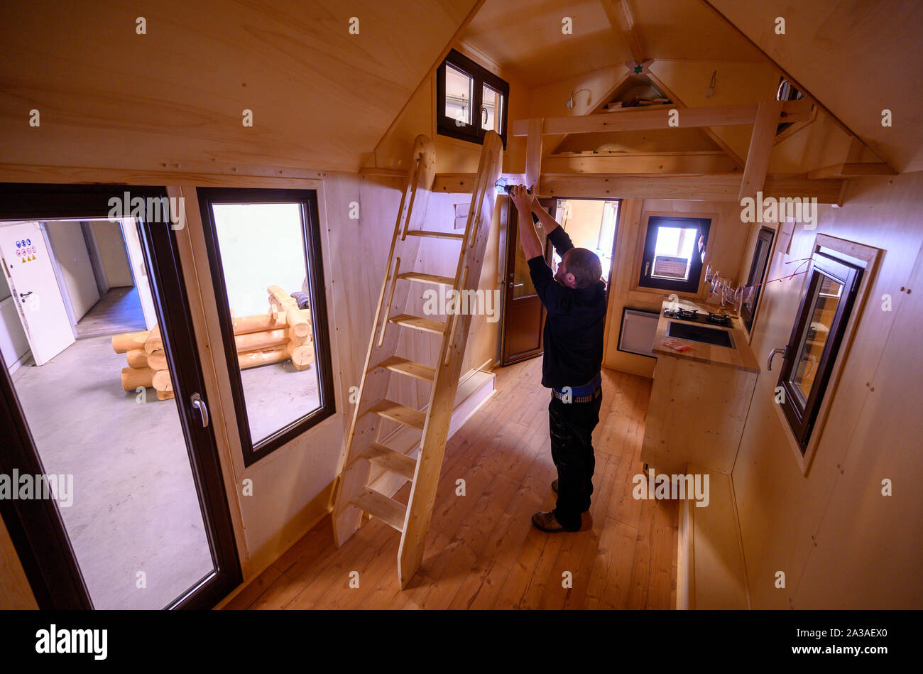 Ludwigslust, Germany. 19th Sep, 2019. Benjamin Glowatzki screws the ladder  to the loft bed in a Tiny House. The mobile homes have been produced in  Ludwigslust since the beginning of the year.