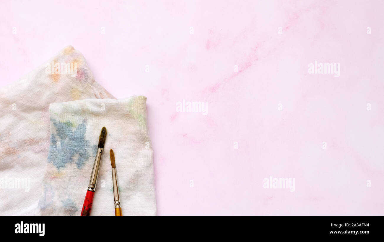 2 watercolor brushes and a cloth with watercolor stain, on a pink background with empty space on the right. Stock Photo