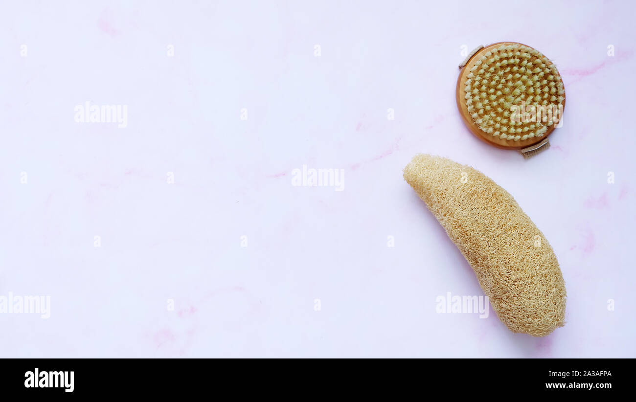 A wooden round body scrub brush and a natural luffa sponge. Stock Photo
