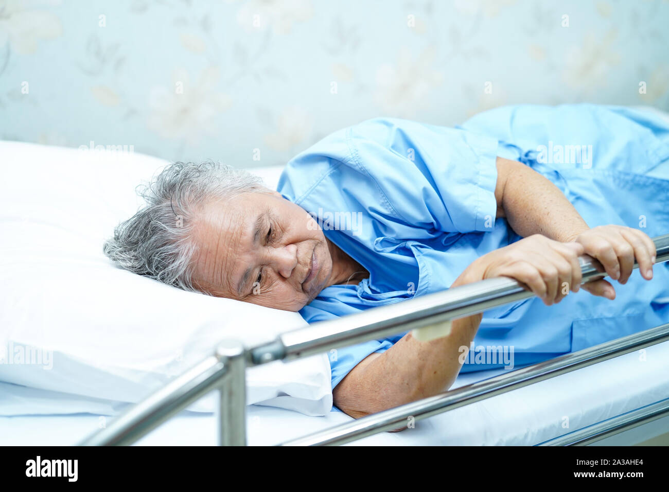 Asian senior or elderly old woman patient lie down handle the rail bed