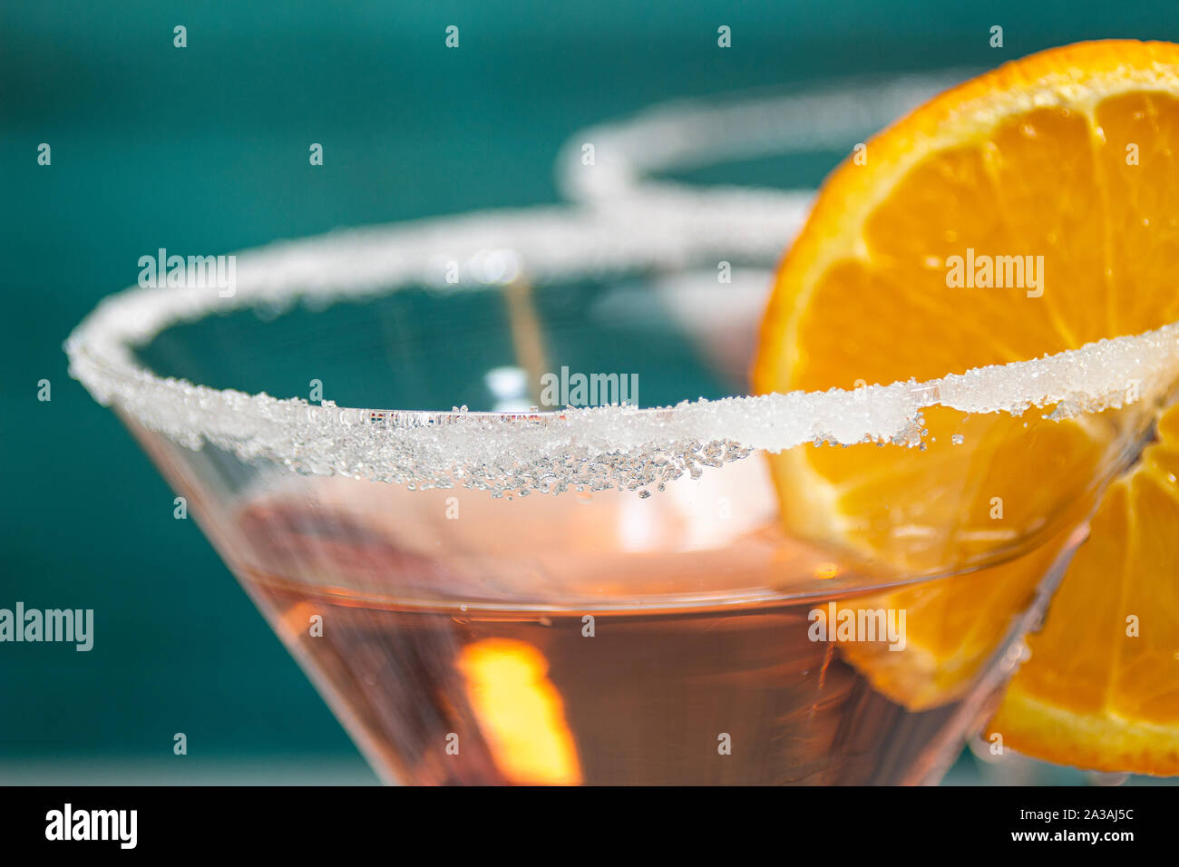 Close up of a cocktail with orange garnish with a green wooden wall Stock Photo