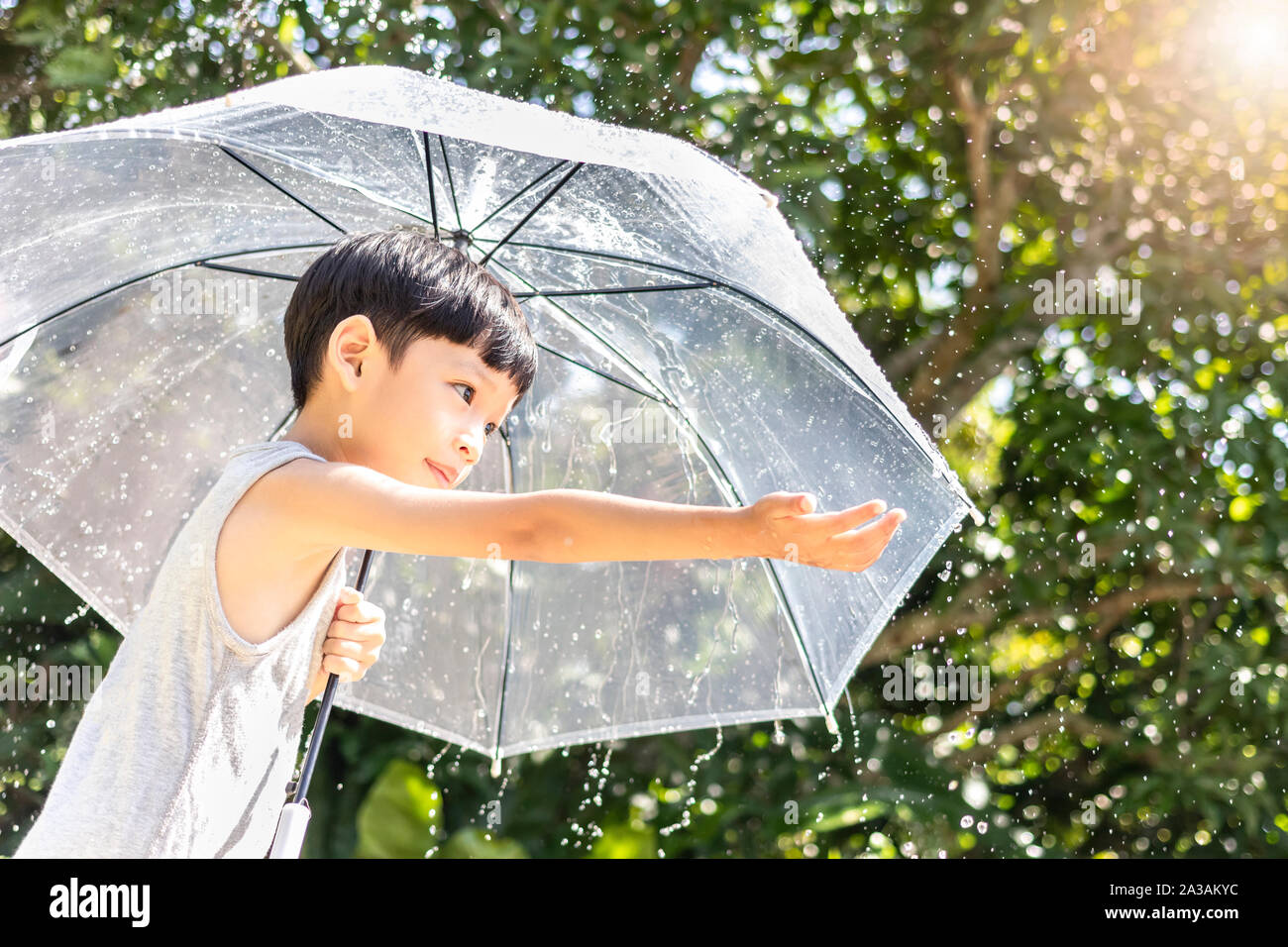 Kid hand holding umbrella playing on the nature outdoors. Little boy hiding under an umbrella. happy kid catching rain drops. Happy funny child  enjoy Stock Photo