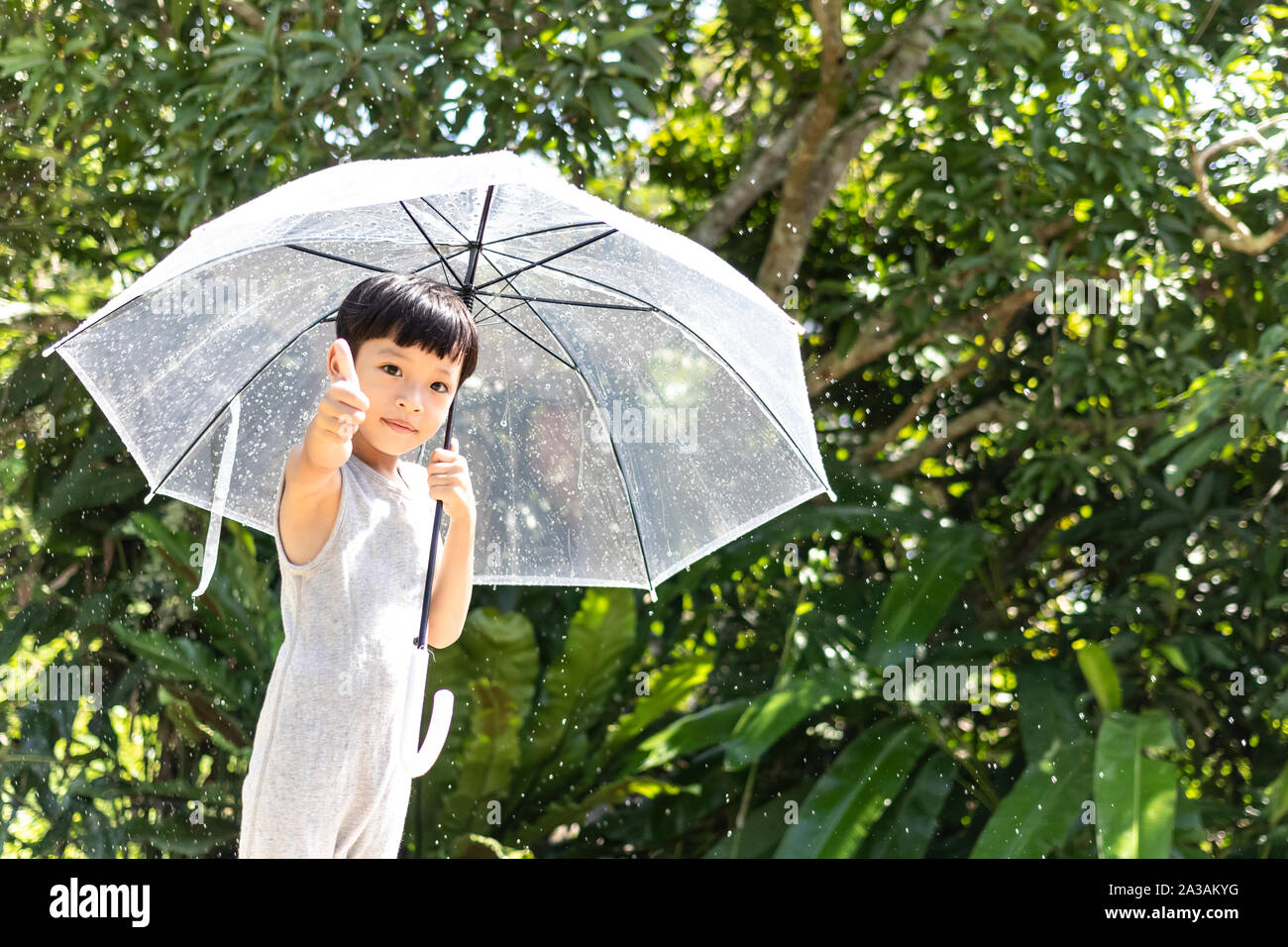 Kid hand holding umbrella playing on the nature outdoors. Little boy hiding under an umbrella. happy kid catching rain drops. Happy funny child  enjoy Stock Photo