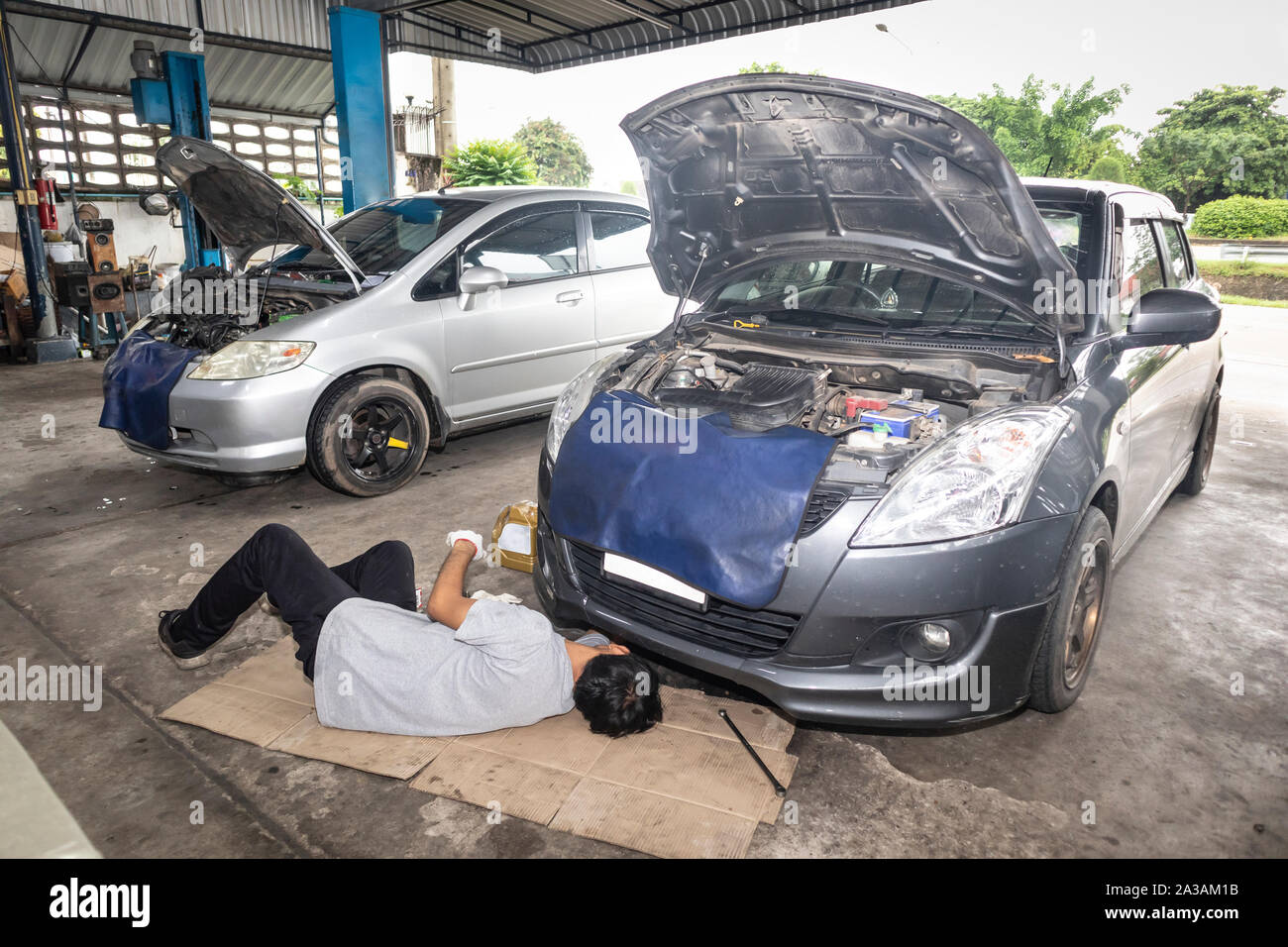Mechanic lying down and working under car at the garage. Mechanics