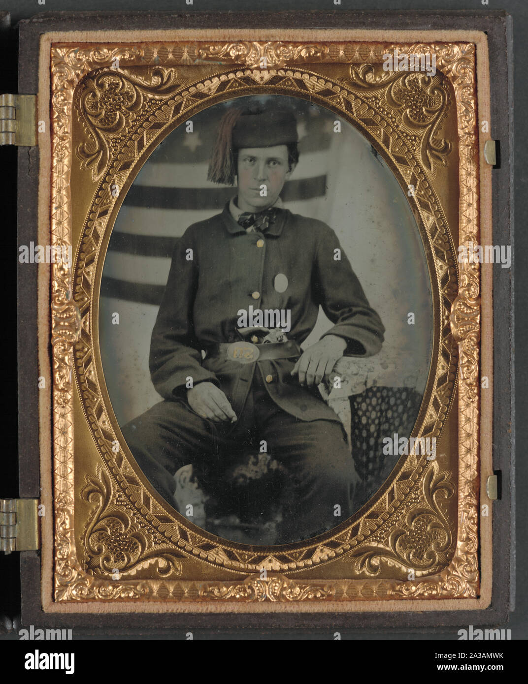Sergeant Albert S. Brownson of Company G, 12th Indiana Infantry Regiment, and Company D, 5th Indiana Cavalry Regiment, in uniform and upside down U.S. belt buckle with revolver in front of American flag backdrop Stock Photo