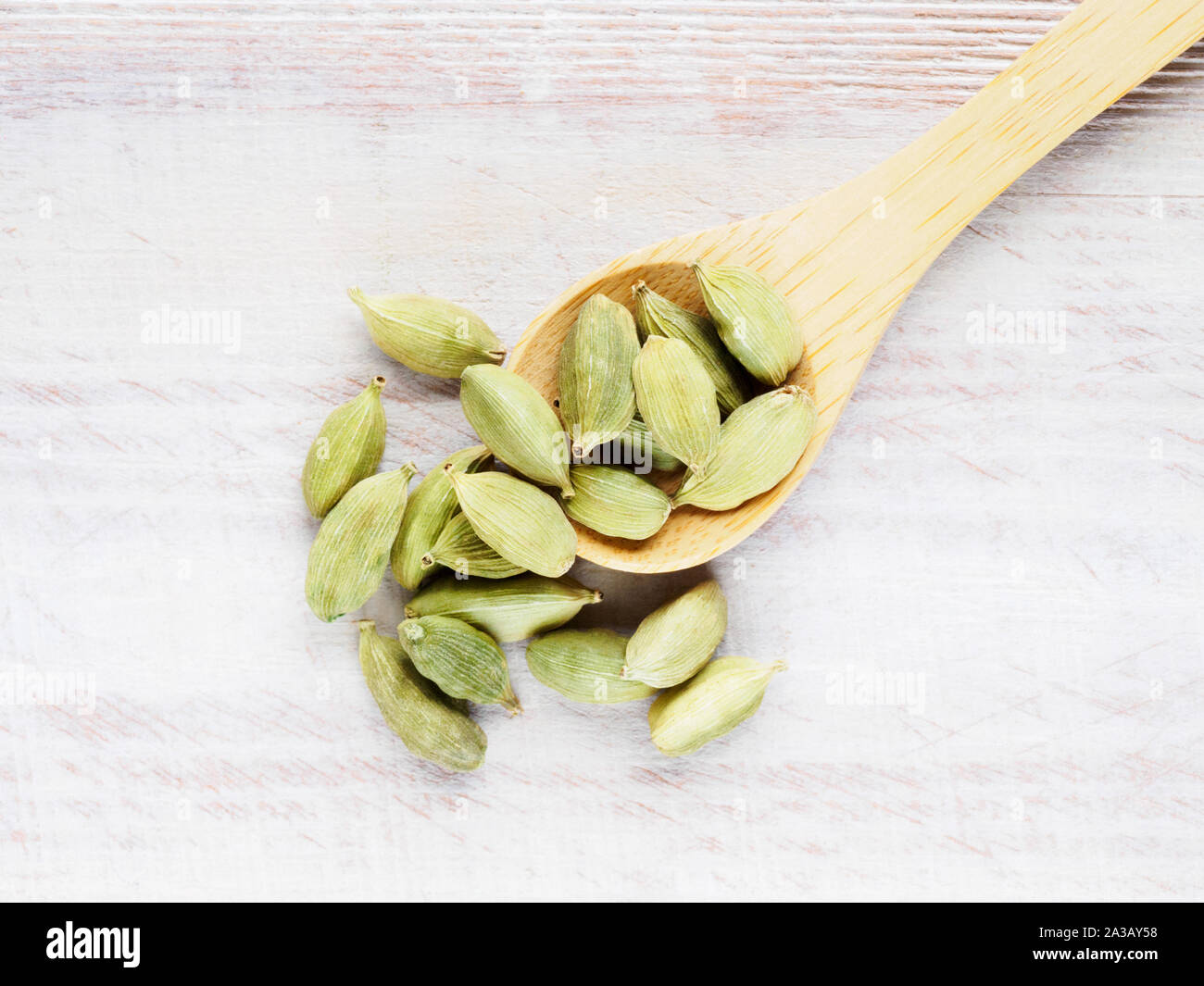 Spice Green cardamom (Elettaria cardamomum) in a spoon diagonally on a brown wooden background Stock Photo