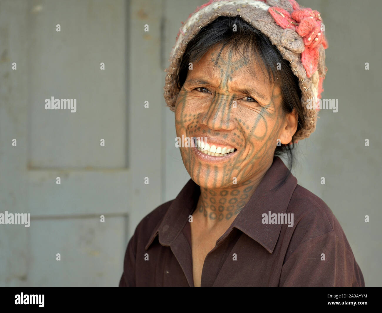 Middle-aged Chin Muun tribal woman ('spider woman') with traditional facial tattoo smiles for the camera. Stock Photo