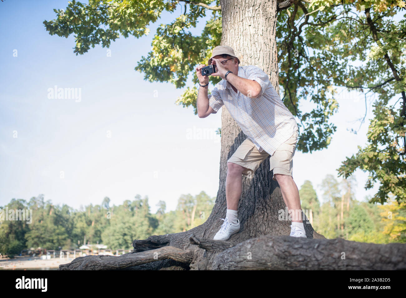 Man taking photo of forest while standing near big tree Stock Photo
