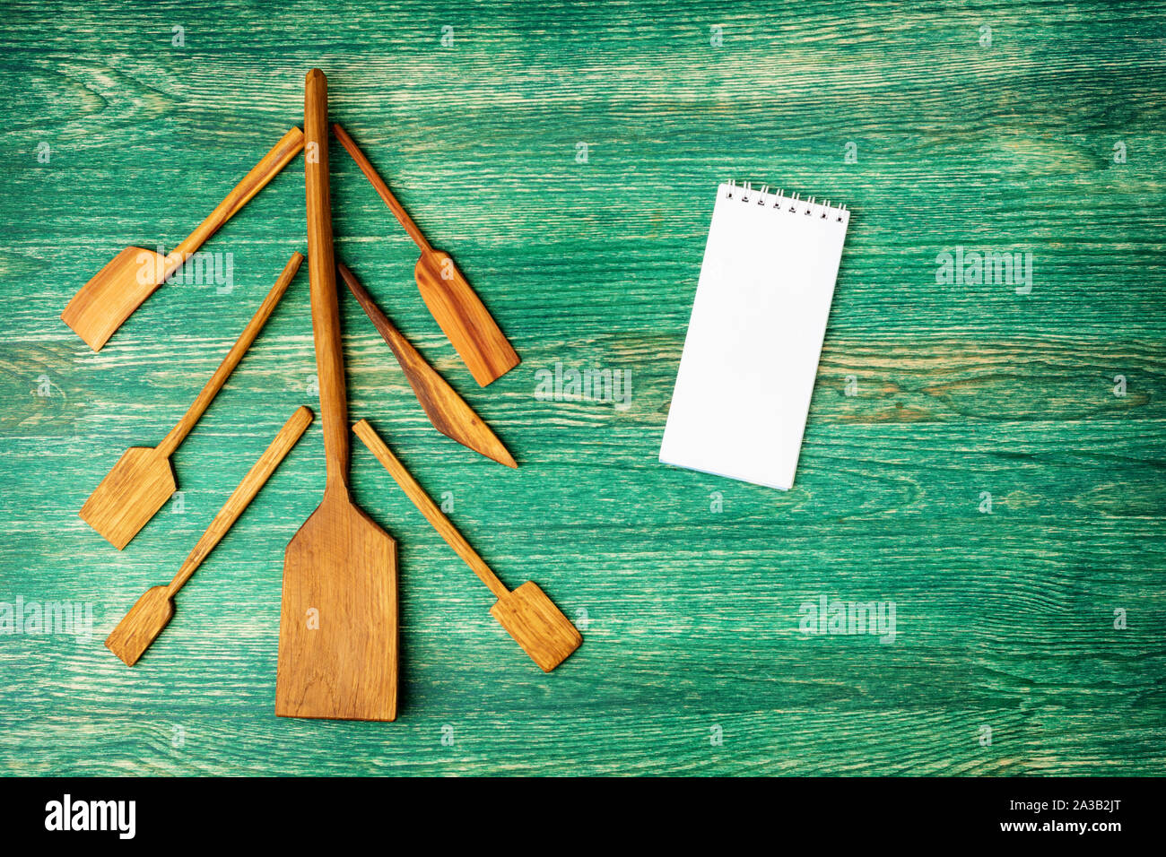 Flat lay background. Christmas tree made of kitchen utelits on old wooden table with notepad and copys pace for text. Stock Photo