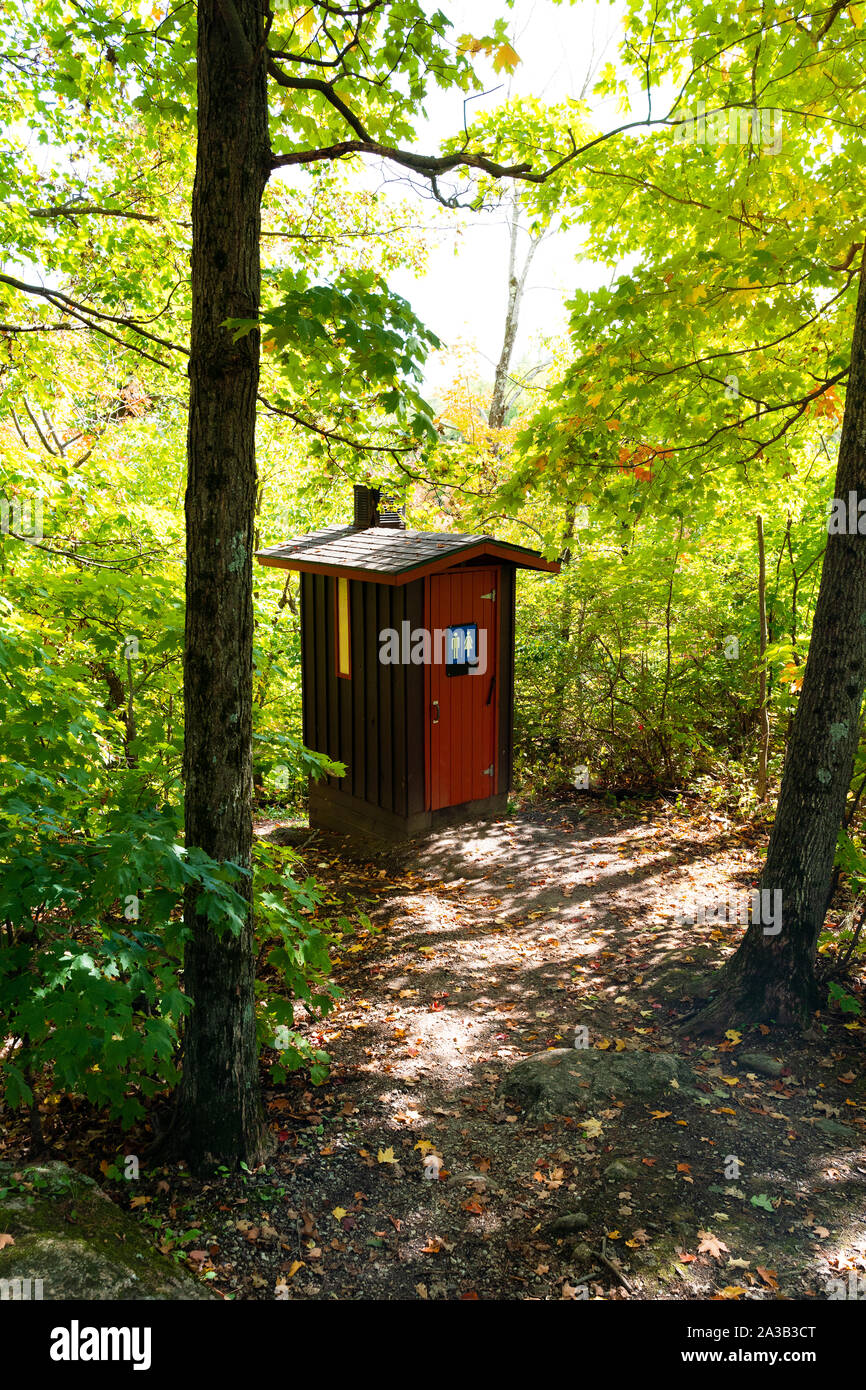 Gorgeous red and brown public toilet in the middle of the woods, Gatineau Park ,Quebec, Canada. Stock Photo