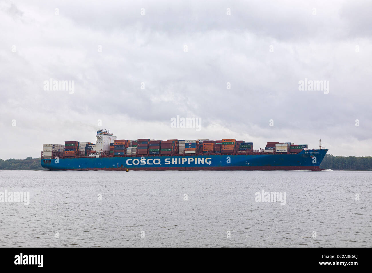 Container ship XIN HONG KONG, owned by China COSCO Shipping Corporation, on Elbe river heading to Hamburg Stock Photo