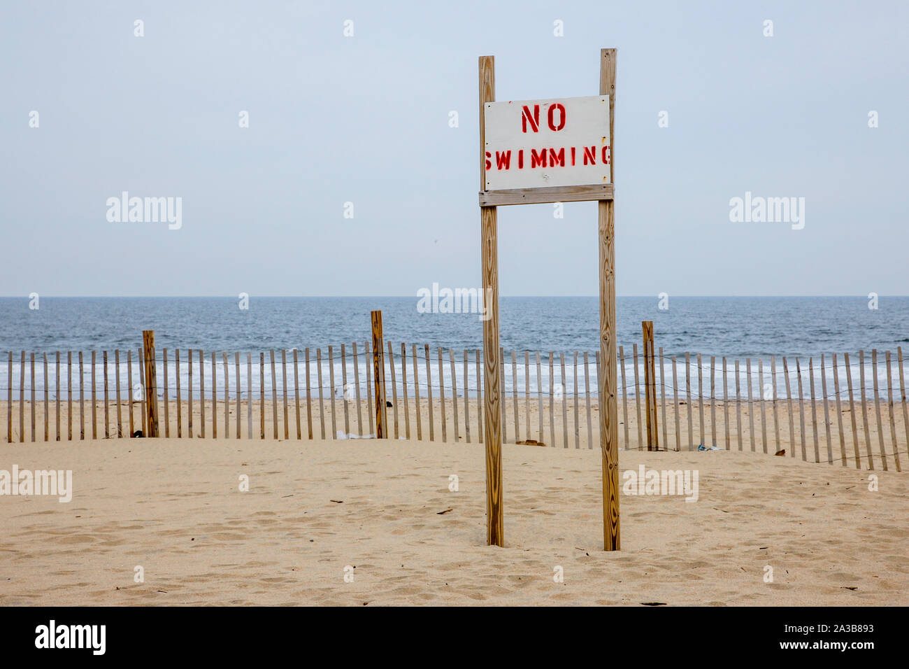 A sign on the beach in Ashbury Park says 'No Swimming'. The East Coast of the US have experienced increased beach erosion and more patches with rough weather and coastal flooding due to climate change. Stock Photo