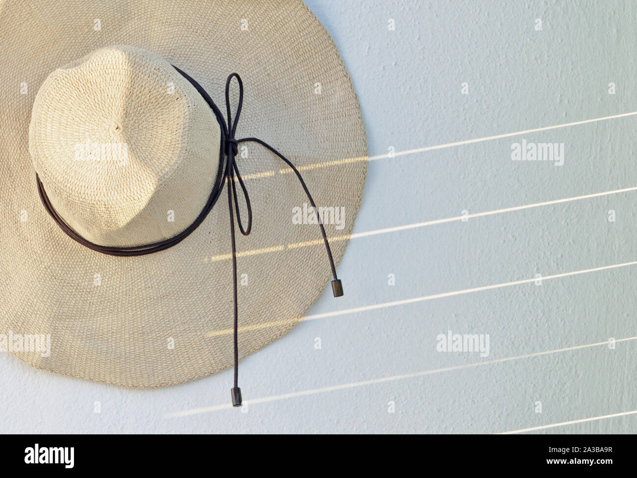 Straw hat hanging on wall Stock Photo