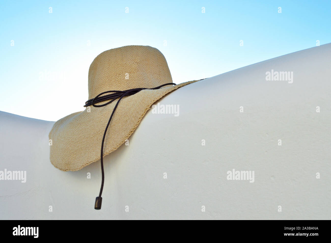 Straw hat on white wall and sky background Stock Photo