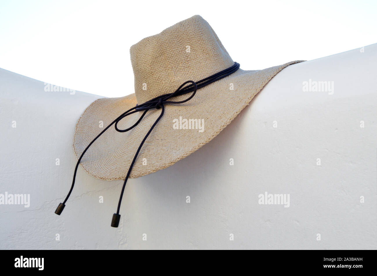 Straw hat on white wall and sky background Stock Photo