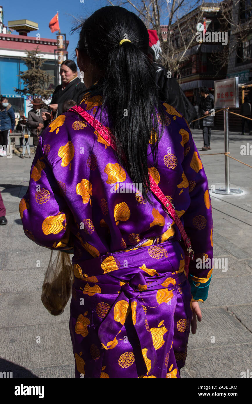 A young girl in a colorful silk dress in Lhasa, Tibet.  The dress appears to be printed with the modern Apple rather than a traditional design. Stock Photo