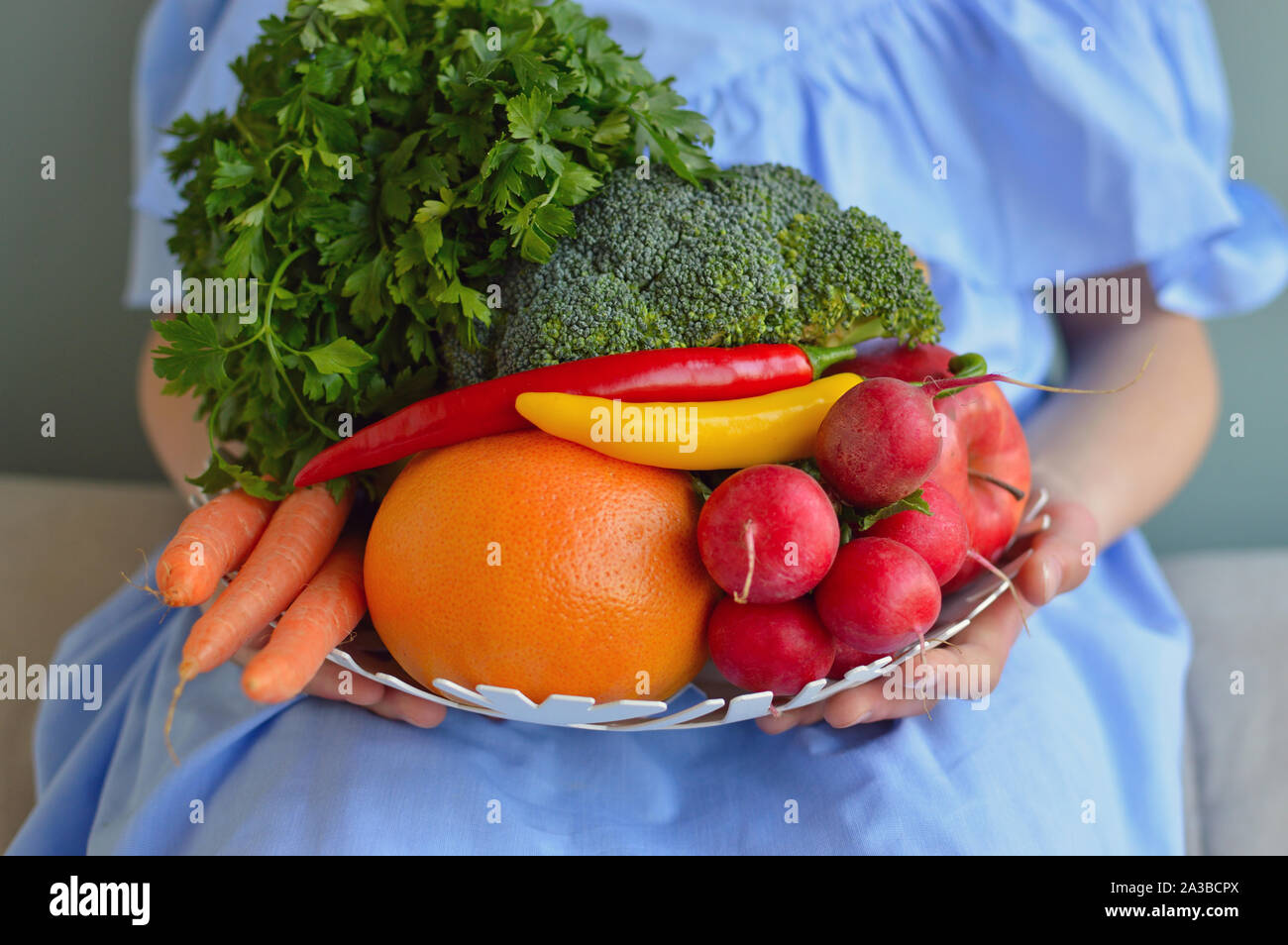 Close up shot of fruits and vegetables bowl held by girl Stock Photo