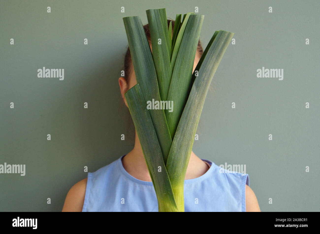 Girl covering face with a leek Stock Photo