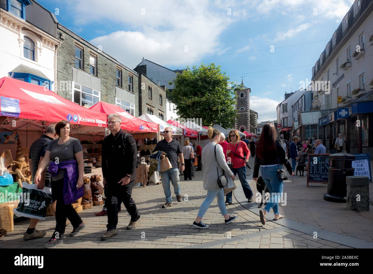 People tourists visitors at the outdoor Thursday market stalls in summer Market Square Keswick Cumbria England UK United Kingdom Britain Stock Photo