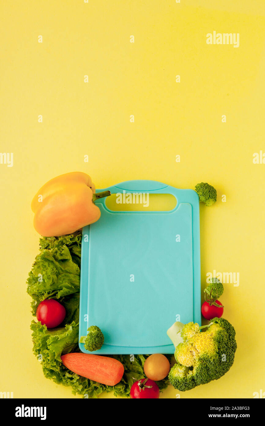 Blackboard with fresh vegetables on yellow background. Concept of Healthy Eating. Stock Photo