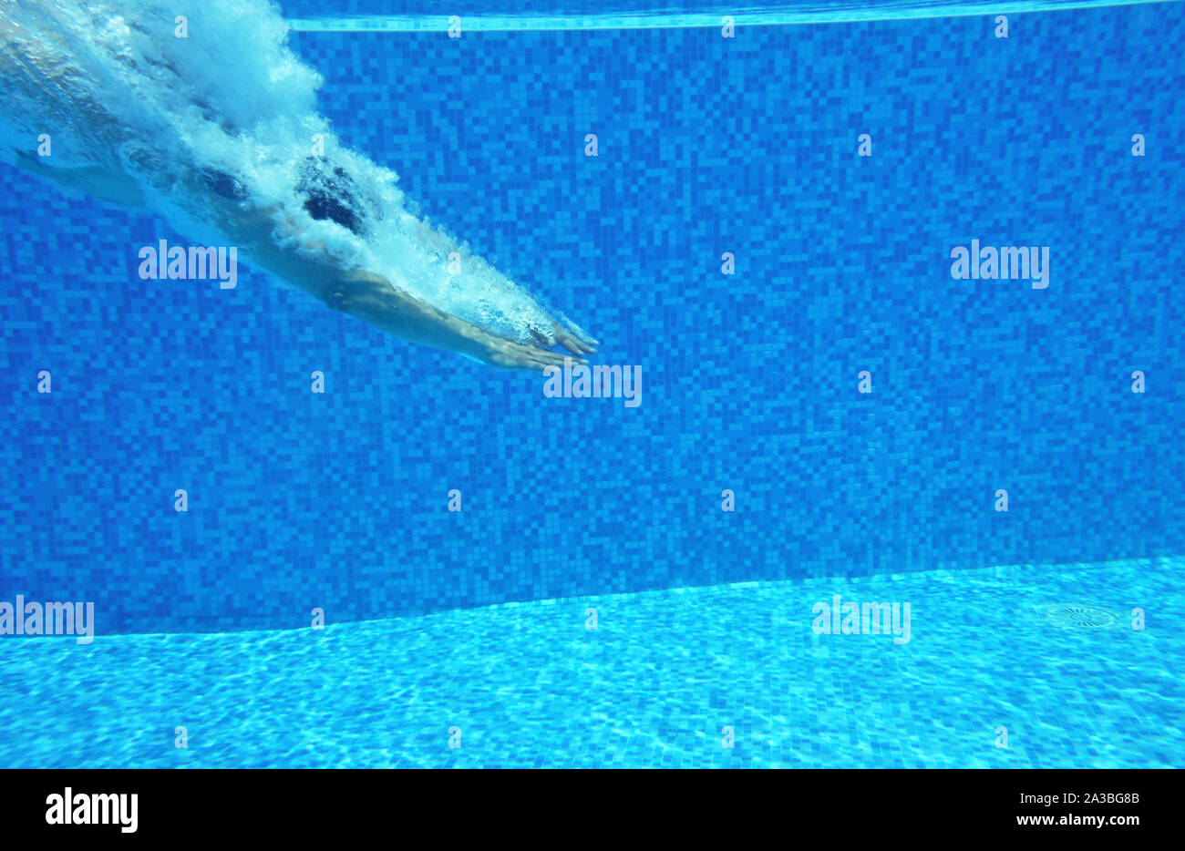 Underwater shot of man diving into pool Stock Photo
