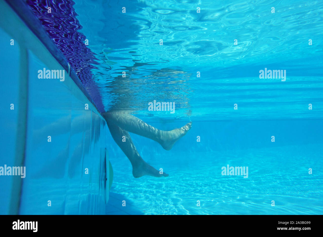 Underwater shot of legs on pool side Stock Photo