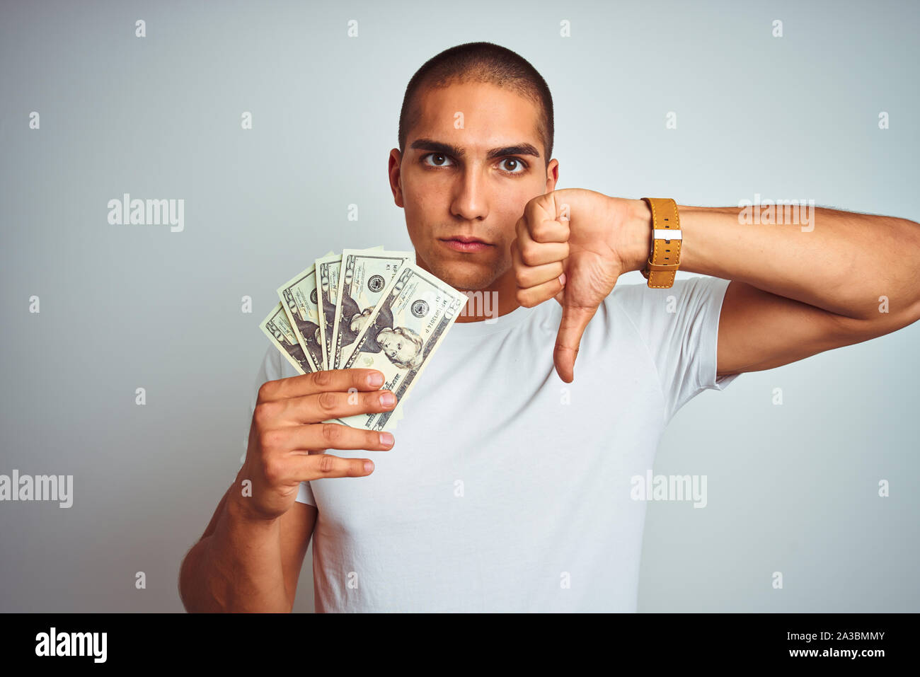 Young handsome man holding dollars over white isolated background with ...