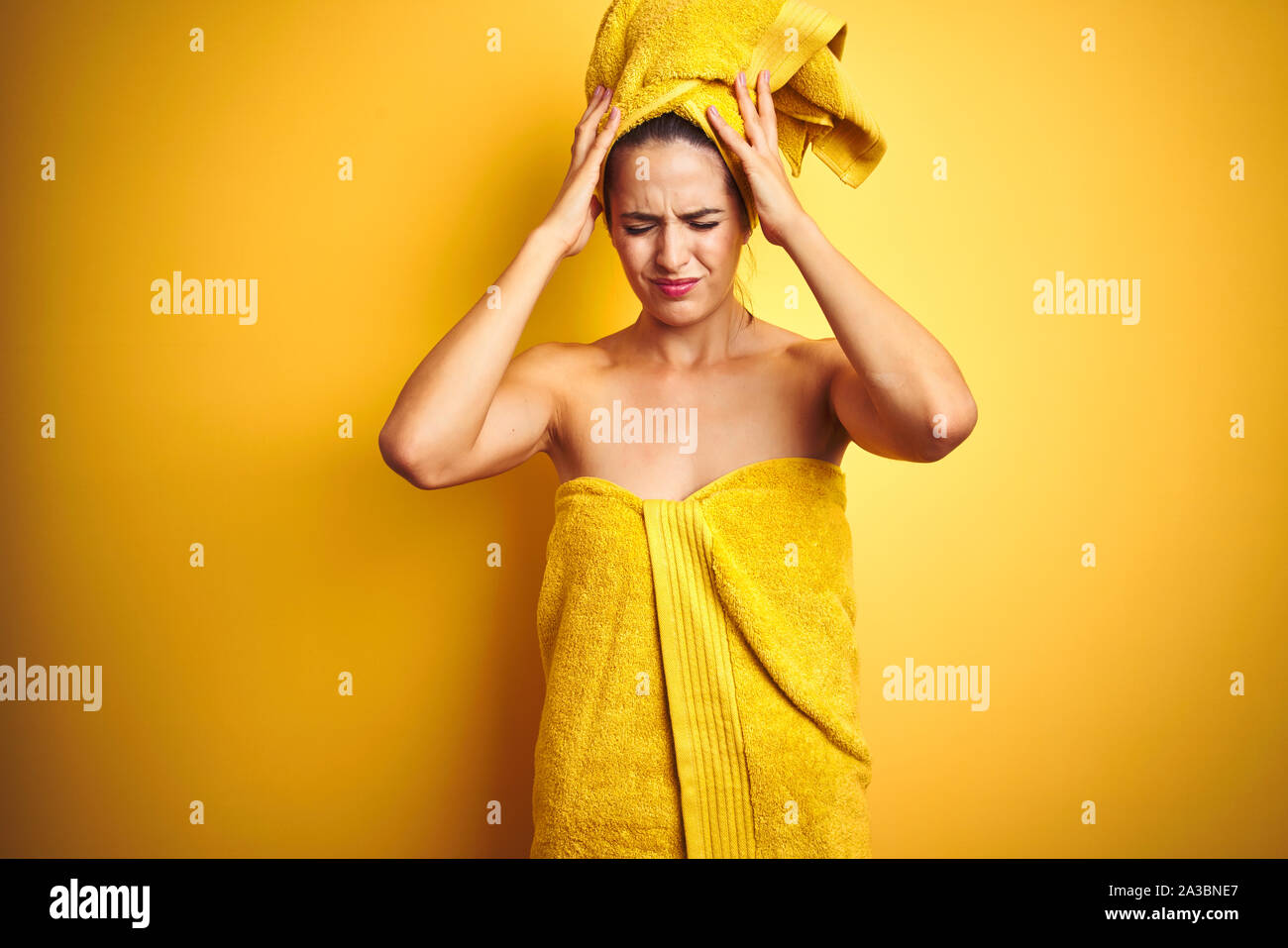 Beautiful woman wearing shower towel on body and head over yellow