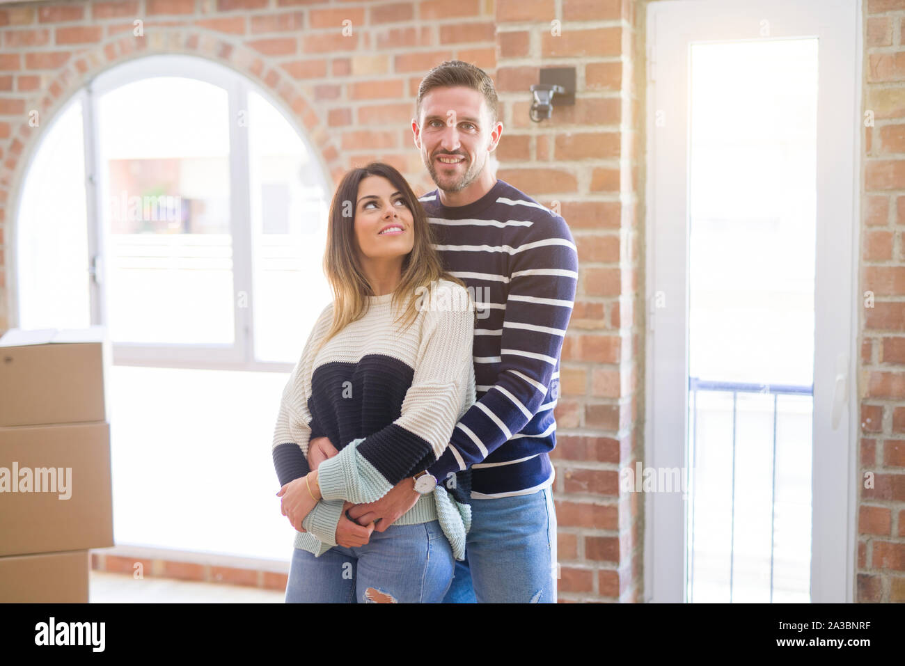 Young beautiful couple hugging at new home around cardboard boxes Stock ...