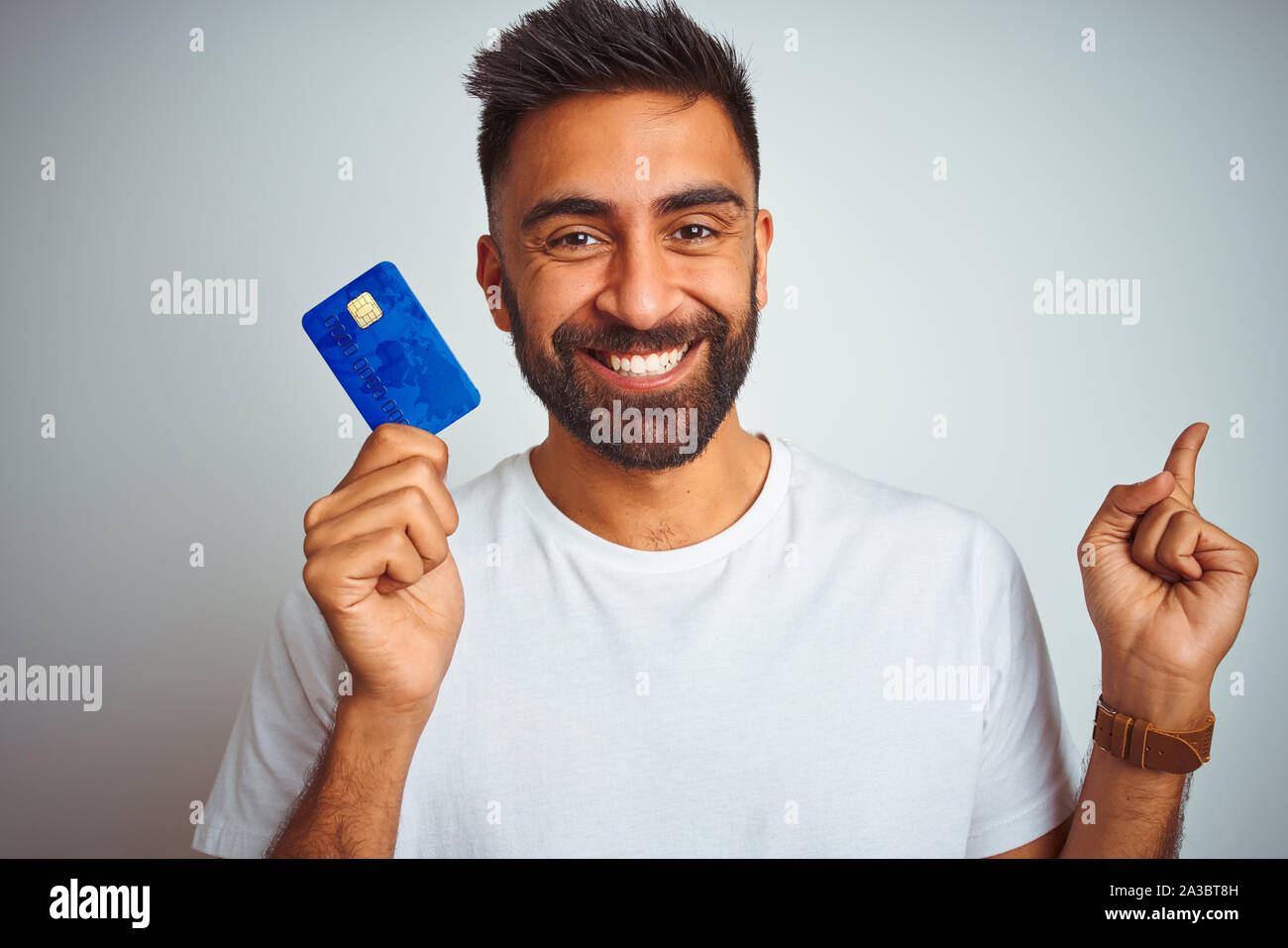 Young indian customer man holding credit card standing over isolated ...