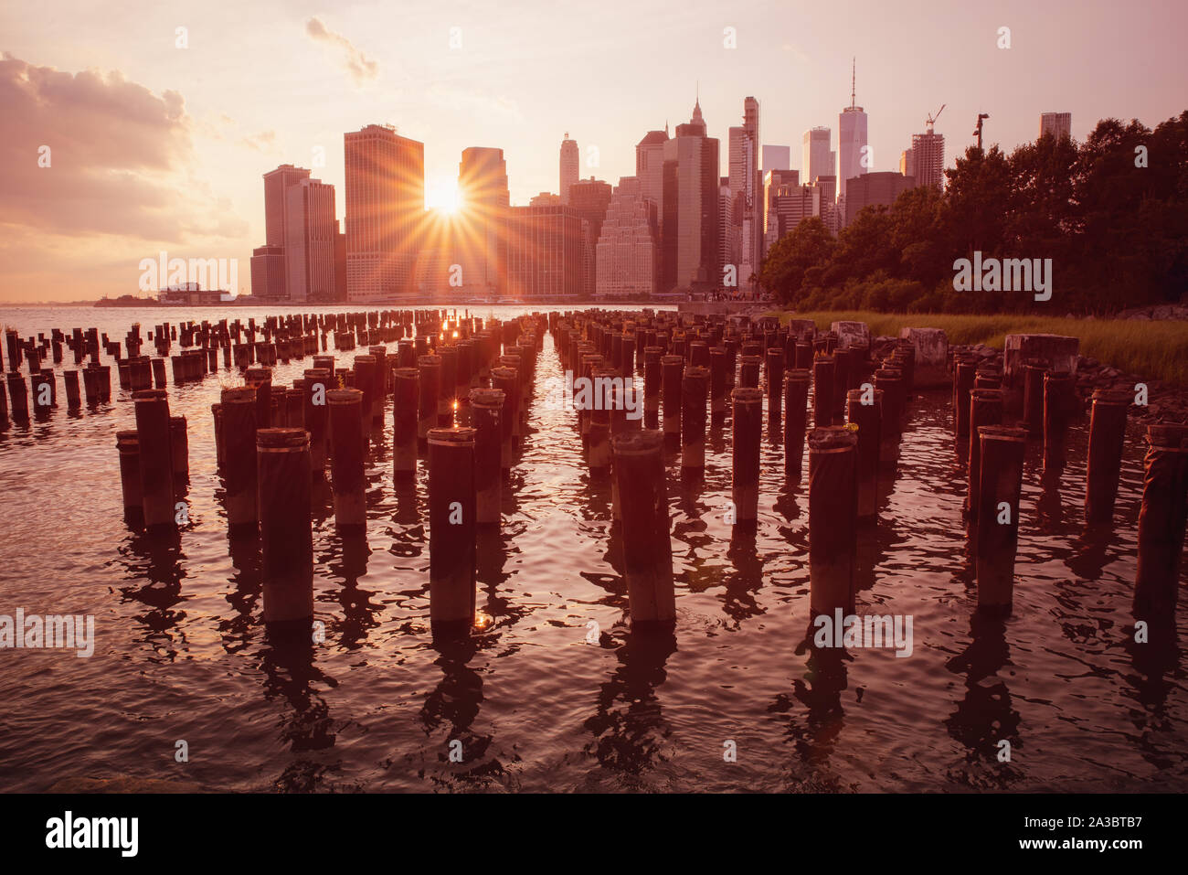 warm sunset on manhattan modern architecture skyline with sun spikes passing through the buildings, Brooklyn old pier, Manhattan New York city Stock Photo