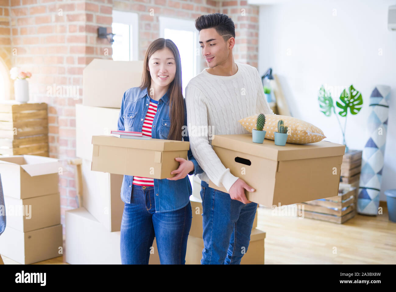 Beautiful young asian couple looking happy holding cardboard boxes ...