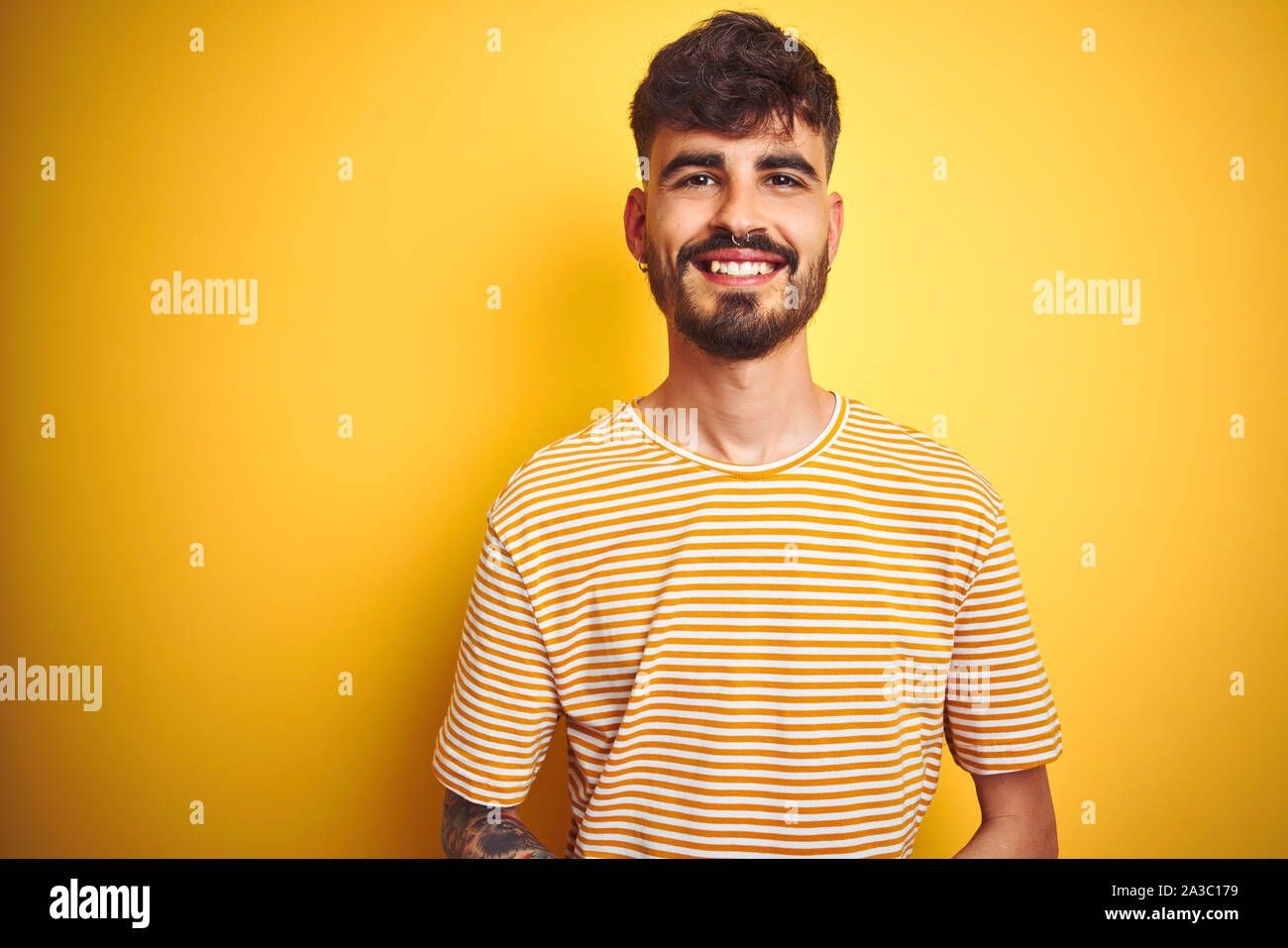 Young Man With Tattoo Wearing Striped T Shirt Standing Over Isolated