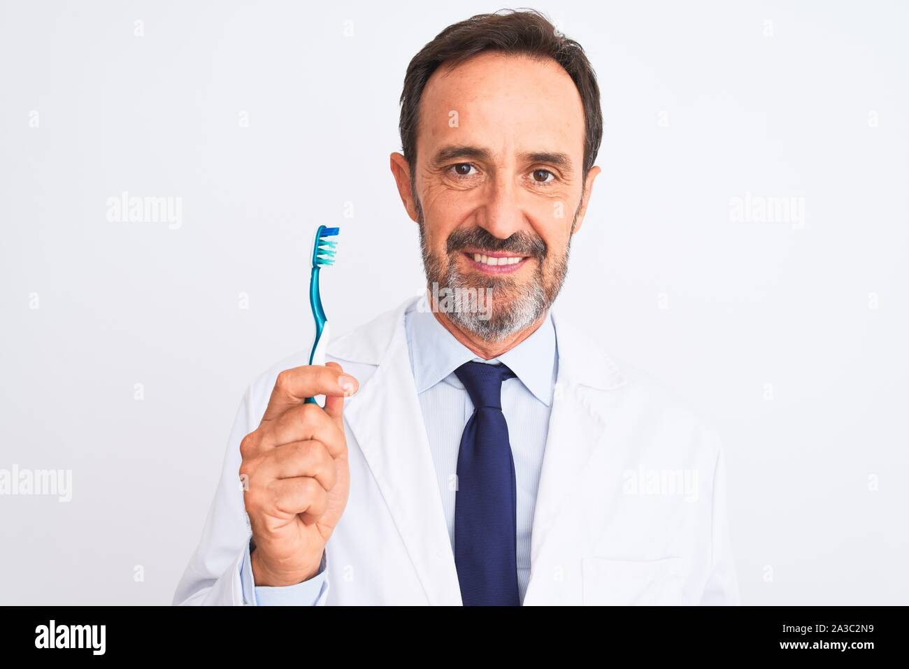 Middle age dentist man holding toothbrush standing over isolated white background with a confident expression on smart face thinking serious Stock Photo