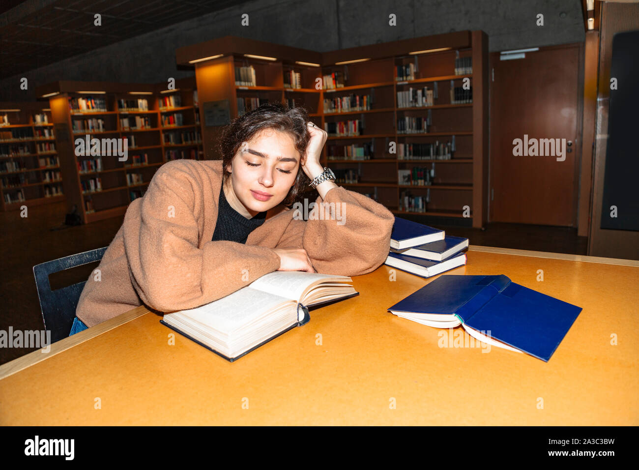 Girl sitting by wooden table and reading book Stock Photo - Alamy