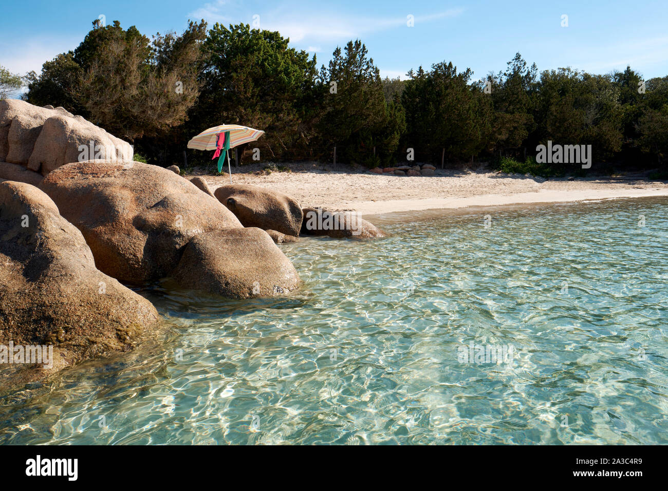 Secluded clear water, white sand beach and rocks with parasol / Plage de Santa Giulia / Santa Giulia beach, Porto-Vecchio Corsica summer beach Stock Photo