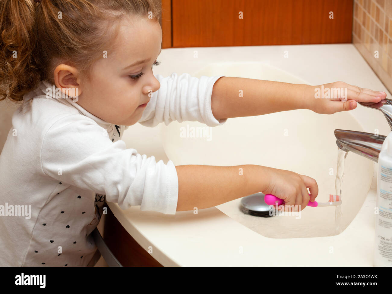 Portrait of cute little girl with blonde hair which cleaning tooth with