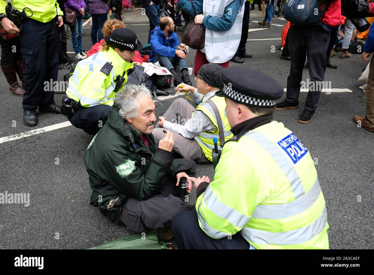 Westminster, London, UK - Monday 7th October 2019 - Extinction Rebellion XR climate protesters block roads around Westminster - Police officers warn a protester of imminent arrest at Millbank near Parliament. Photo Steven May / Alamy Live News Stock Photo