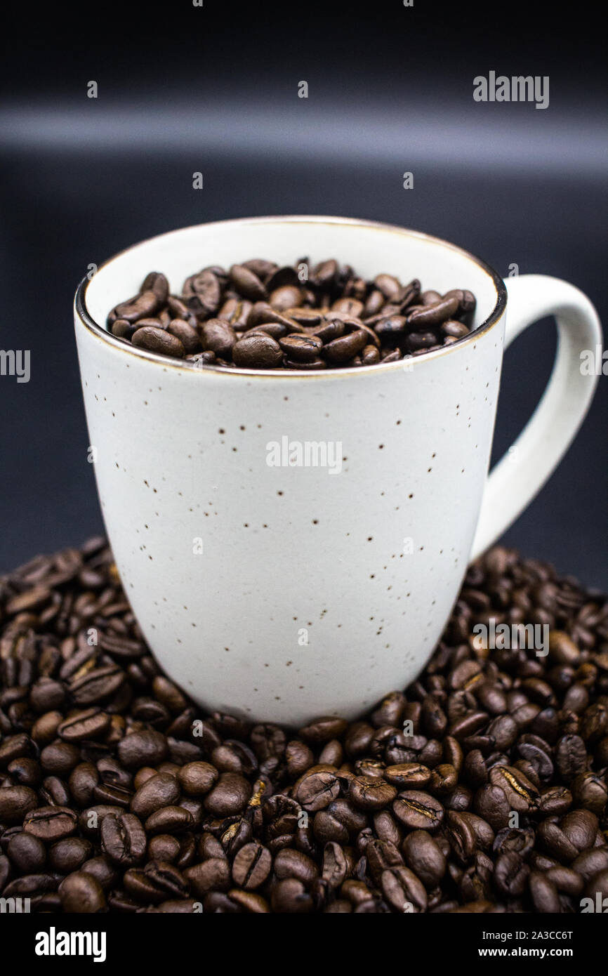 White Mug of Coffee Beans on top of Coffee Beans Stock Photo