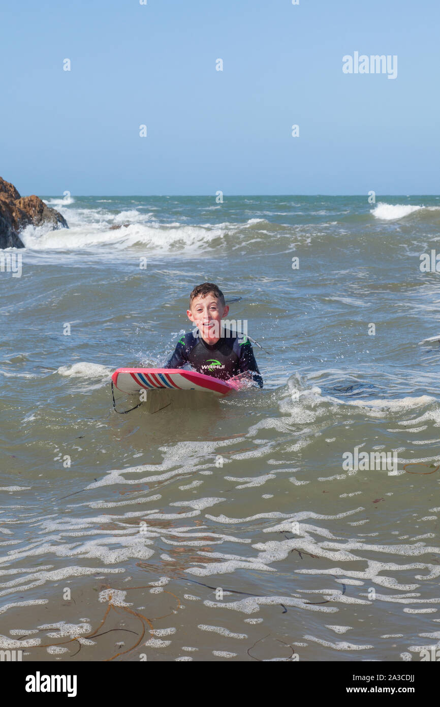 Ten year old boy surfing at Outer Hope Cove, Mouthwell sands beach, Kingsbridge, Devon, England, United Kingdom. Stock Photo